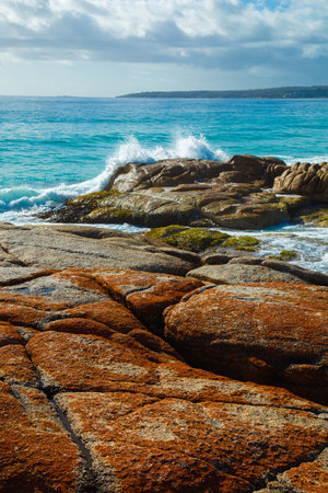 Wave breaking on the orange rocks at Bay of fire in Tasmania.の写真素材