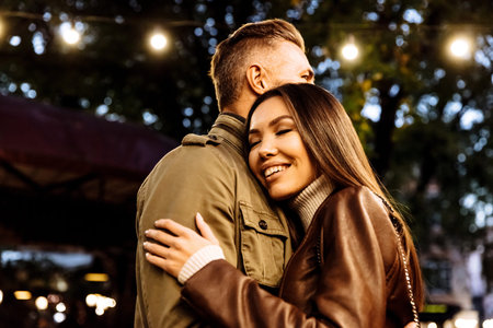 Evening autumn walk. Couple. Love. Man and woman in warm casual clothes are hugging  and smiling while walking in the parkの写真素材