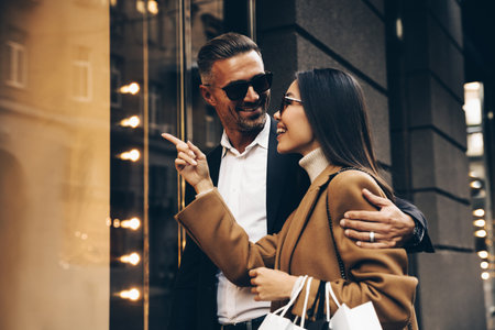 Shopping. Black Friday. Couple. Love. Man and woman with bags are looking at the shopping windows and smiling while walking down the streetの写真素材