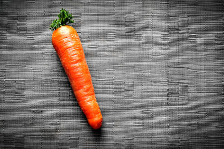 Carrots on black synthetic fabric background の写真素材