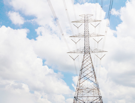 Electric transmission line tower with cloudy skyの写真素材