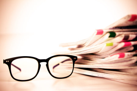 selective focus on reading eyeglasses with stacking of the newspaper background