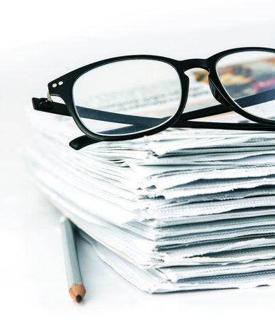 the reading eyeglasses with stacking of newspaper background