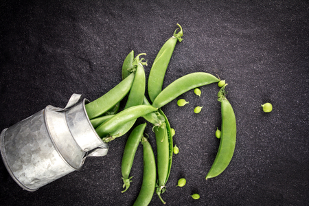 the fresh green sweet peas  on black stone backgroundの写真素材