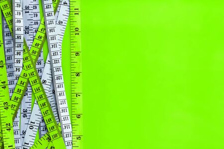 Diet control concept background. Colorful of Measuring tape on vibrant green color  background.の写真素材