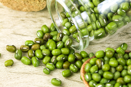 close up the green mung beans in wooden spoon on wood plateの写真素材