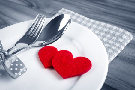 red heart shape with White empty plate with fork and spoon on wooden table for love dinner conceptの写真素材