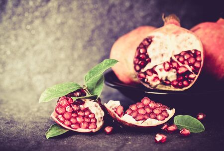 Fresh red pomegranate and seed  with leaves over black stone background , vintage color toneの写真素材