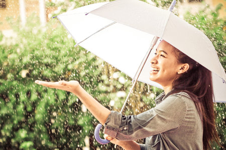 The smiling girl hold on umbrella with happy with rainの写真素材