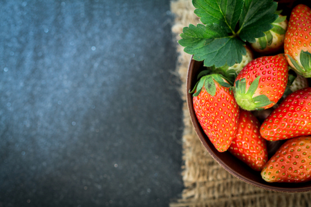 Close up Top view of Red Strawberries and leaf with black stone backgroundの写真素材