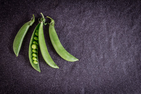the fresh green sweet peas  on black stone background