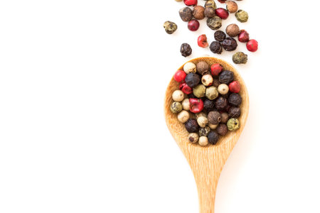 Close up mixed type of peppercorns in wooden spoon on white background , top view or overhead shot