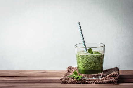 the Healthy fresh  green smoothie juice in the drinking glass on wooden table for healthy detox and diet  habits conceptの写真素材