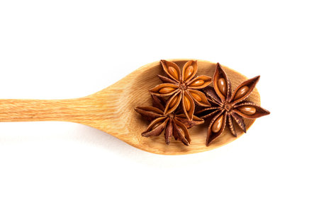 Close up brown star anise spice in wooden spoon isolated on white background