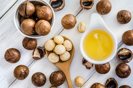 The Macadamia Nut Oil and peeled macadamia nut   on white table ,?use for Healthy Skin and Hair and Natural Healing Oil Treatment , overhead and top viewの写真素材