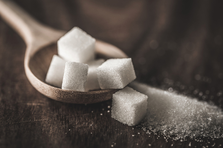 Close up sugar cubes and cane in wooden spoon on the table ,retro color toneの写真素材