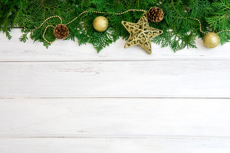 The Pine leaf with yellow gold star and christmas ball decoration on white wooden board with copy...