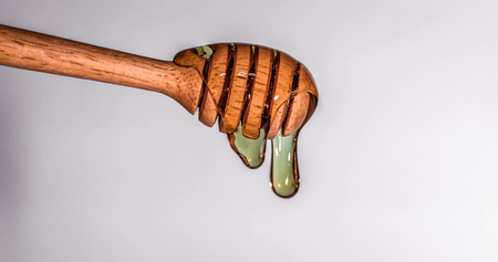 Close up pouring golden sweet honey dripping  on honey dipper  vintage retro color  backgroundの写真素材