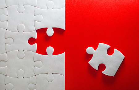 Close up piece of white jigsaw puzzle on red , concept of business challenge completion with teamworkの写真素材