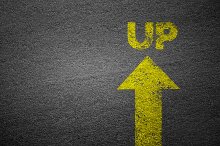 Grunge Yellow arrow with UP text on rough black texture , sign of success , growth of business conceptの写真素材