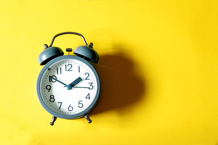 Alarm clock on bright  yellow background , time management concept