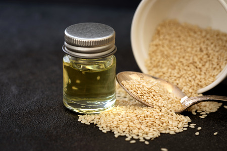 organic  white sesame seeds in wooden spoon with oil bottleの写真素材