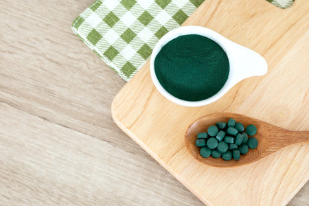 Close up  a spirulina powder  and spirulina pills in spoon , healthy superfood diet and detox...