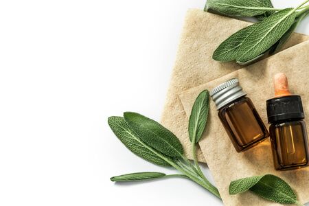 Close up fresh green sage herb leaf with bottle of essential oil on white background , herb essence conceptの写真素材