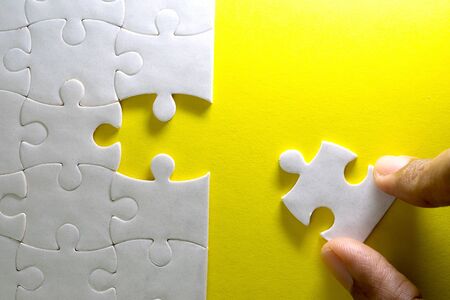 Close up piece of white jigsaw puzzle, concept of business challenge completion with teamworkの写真素材