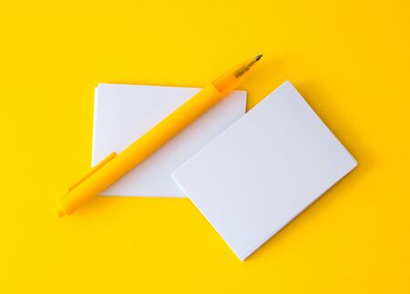 stacking of mockup empty white business card with elegance pen  on vibrant yellow background , template for business  branding  designの写真素材