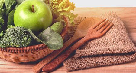 close up green apple with mixed green vegetable in a basket and wooden fork and spoon for healthy organic green food conceptの写真素材