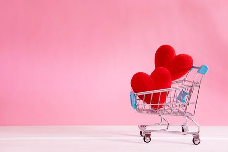 The red Heart shapes  in shopping cart on sweet pink background , love concept for shopping on valentines day with sweet and romantic momentの写真素材
