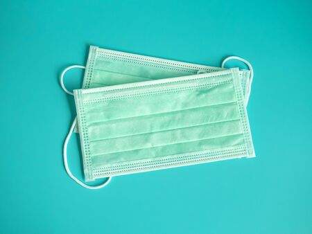 close up white surgical face mask on blue green background , equipment mask to protect man health from flu , coronavirus infection , Health care conceptの写真素材