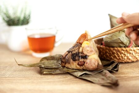 Close up Zongzi or rice dumpling on wooden table with Chinese tea in Dragon Boat Festival, eating zongzi by chopstick Asian traditional foodの写真素材