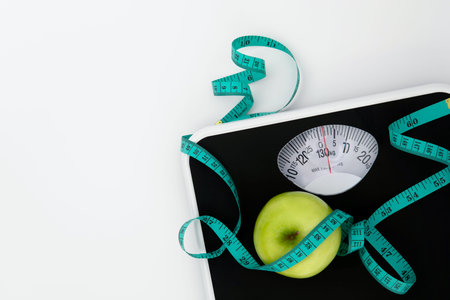 Weight scale and measure tape with fresh apple on white background with copy space , Weight loss or...
