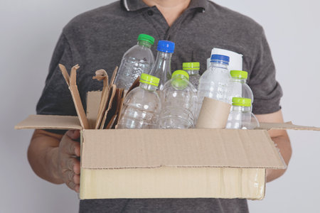 Man hold box of sorting  plastic bottle and paper garbage waste to proper recycling box , recycle or reuse to take care environment conceptの写真素材