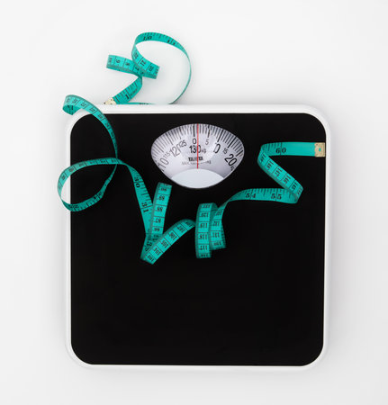 Weight scale and measure tape on white background with copy space , Weight loss or healthy diet control to slim healthy body conceptの写真素材