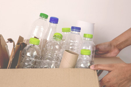 hand holding plastic bottle waste for sorting  plastic bottle and paper garbage waste to proper...