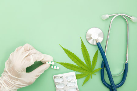 Marijuana leaf with stethoscope and doctor hand holding drug capsule on light green background , Medical using of marijuana cannabis plant product conceptの写真素材