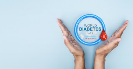 Hand hold up on blue circle symbolic of Diabetes awareness with red drop of blood on world map background for poster and banner for World Diabetes Day conceptの写真素材