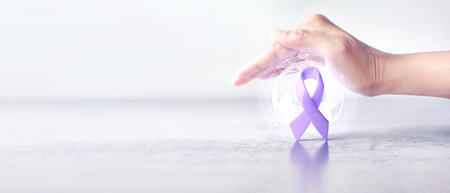 Hand cover over protect lavender color ribbon awareness symbolic for banner of World Cancer Day or cancer awareness conceptの写真素材