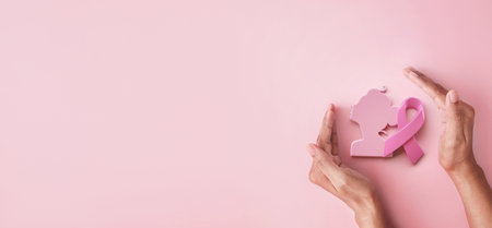 Hand hold protection pink ribbon and women symbol for Breast Cancer Awareness symbolic on pink background, protect and monitor breast cancer promote in October month campaign conceptの写真素材