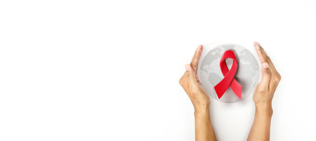 Hand covered 3d red ribbon on lighten world map background, campaign for World AIDS Day on 1 Decemberの写真素材