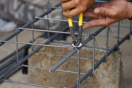 the worker's hand tying reinforcing steel bars, tightening wire on rebar using a pincers for formwork construction,selective focusの写真素材