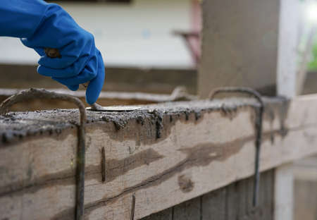 wear glove hand of industrial bricklayer hold  aluminium brick trowel installing mortar wall on construction site, selective focusの写真素材
