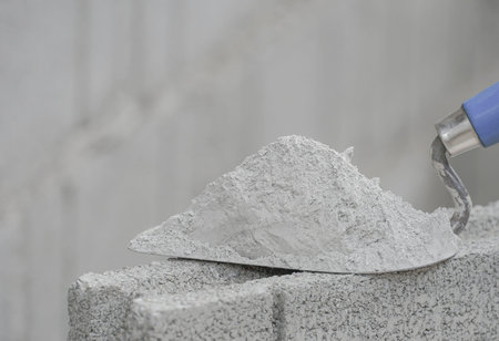 mortar pile on trowel put on a brick block in construction site with copy space for text, selective...