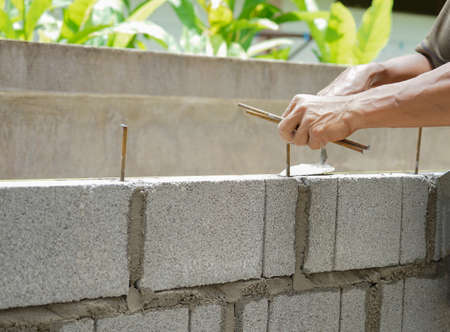 man's hands  of industrial bricklayer with  steel bar installing brick blocks on construction site, selective focusの写真素材