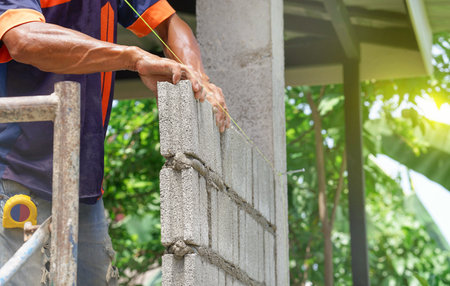 masonry worker hand is doing brickwork on house wall