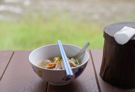 marinated pork ball noodles in a bowl (selective focus)put on wooden table balcony in the noodle shop, background blurred nature atmosphereの写真素材