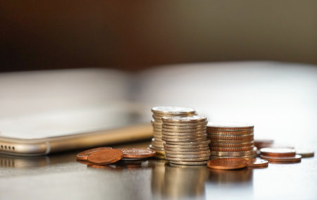 pile and stacking Thai coins (selective focus) with blurred mobile phone background. technology financial services  conceptの写真素材